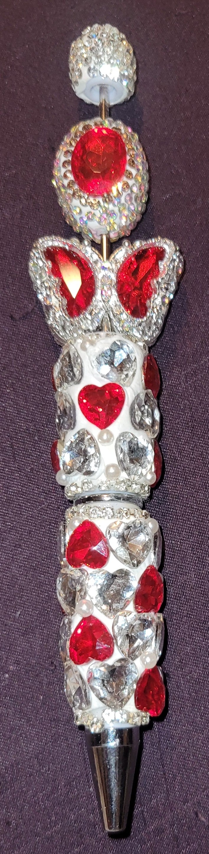 Decorative pen with red gemstones and silver accents on a dark background