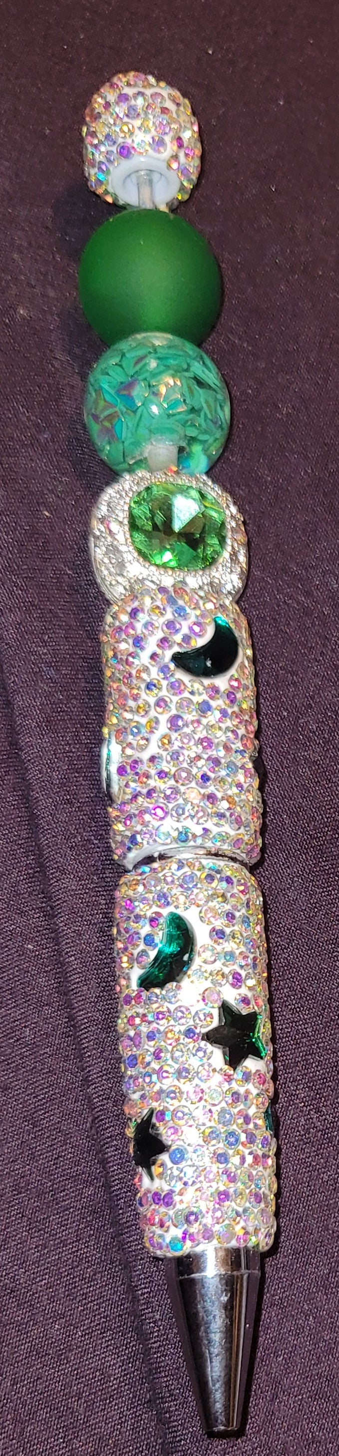 Decorative pen with gemstones and crystals on a purple background