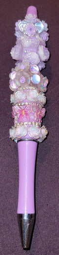 Decorative pen with purple and pink accents on a dark background